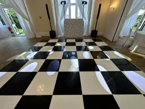 Black and white chequered dance floor in front of a wedding DJ setup
