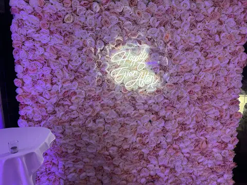 Happily Ever After neon sign displayed on a pink and lavender flower wall
