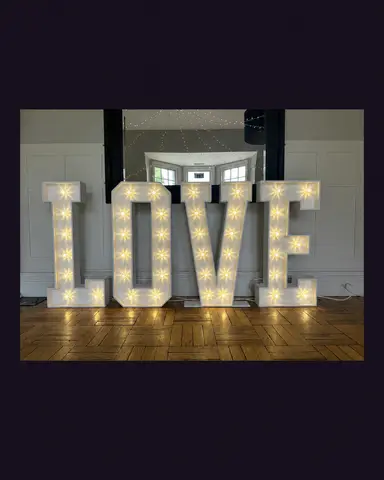 White illuminated LOVE letters displayed in front of a wall mirror.