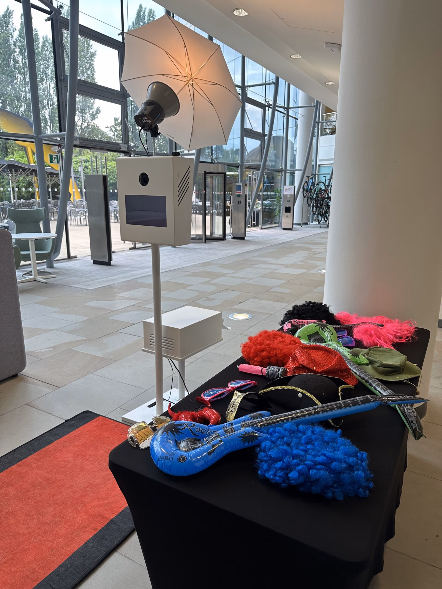 Open photo pod setup with an umbrella flash and a table of colourful photo props