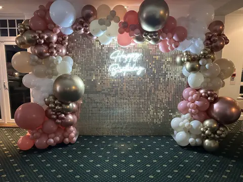 Silver shimmer wall photographed with a Happy Birthday sign and balloons